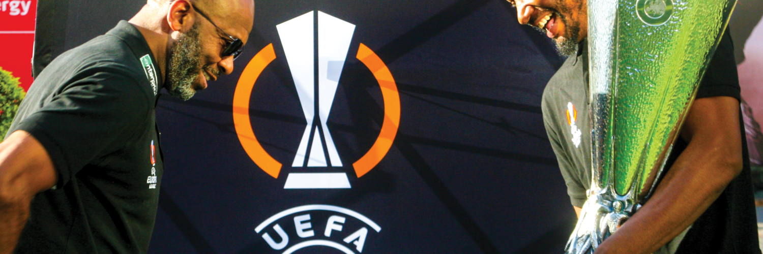 Lucas Radebe and John Obi Mikel seen about to place the UEFA Europa League trophy on a pedestal on the fan viewing area of Melrose Arch Piazza.