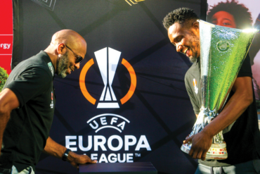 Lucas Radebe and John Obi Mikel seen about to place the UEFA Europa League trophy on a pedestal on the fan viewing area of Melrose Arch Piazza.