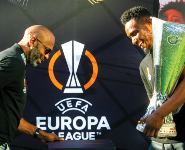 Lucas Radebe and John Obi Mikel seen about to place the UEFA Europa League trophy on a pedestal on the fan viewing area of Melrose Arch Piazza.