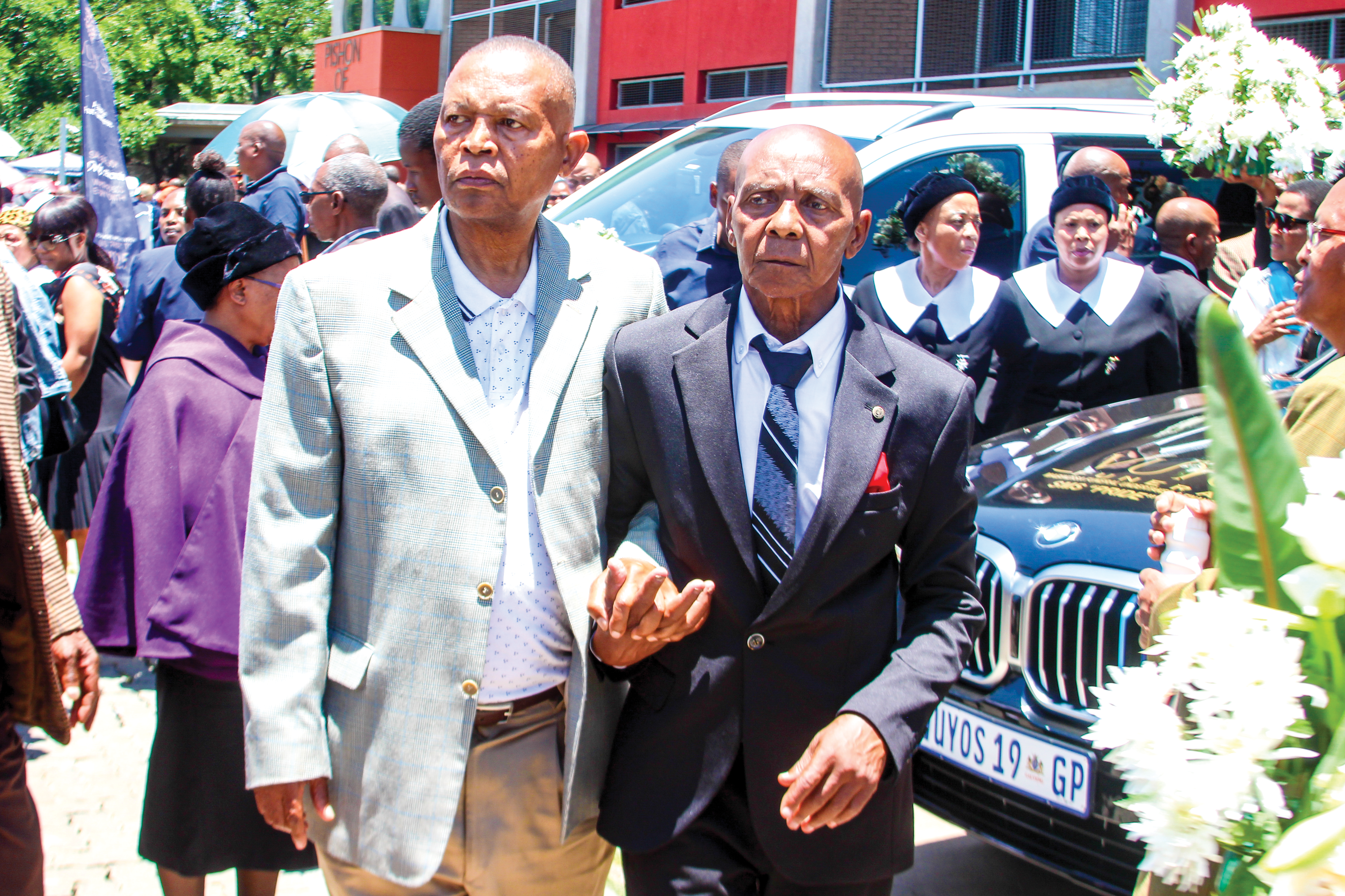 Johannes ‘’Skipper’’ Khomane depicted being escorted outside the Soweto UJ Campus’ hall during the funeral service of his wife, Rita and his son, Papi